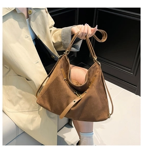Detail of brown suede tote bag with leather straps and vintage brass buckles