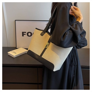 Detail of canvas tote bag with black leather trim and elegant golden metal buckle closure