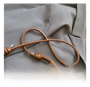Détail d'un sac en cuir marron avec poignée en corde tressée et boucles en métal