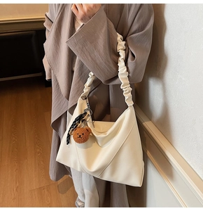 Détail du sac cabas blanc cassé avec bandoulière froncée et breloque petit ours