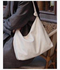 Close-up of cream white hobo bag with knotted shoulder strap and soft leather texture