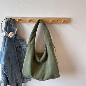 Détail d'un sac cabas en velours côtelé vert montrant la texture et la bandoulière
