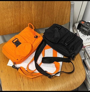 Detail of tactical crossbody bag with industrial buckle and drawstring on wooden chair