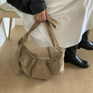 Close-up of khaki crescent bag featuring suede texture and knotted shoulder strap detail