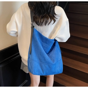 Model wearing a large Klein blue suede tote bag with an adjustable black shoulder strap