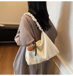 Détail d'un sac hobo blanc en cuir texturé avec une bandoulière froncée et décorative