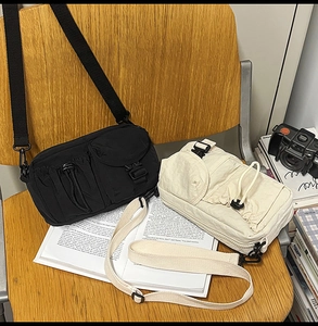Detail of black and beige nylon messenger bags with multi-pockets on a wooden chair