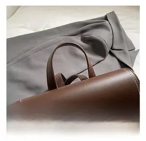 Detail showing the brown leather handle and white stitching of the fashion backpack