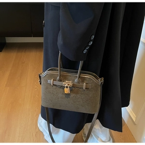 Détail d'un sac coquille en daim vert foncé avec cadenas doré et bandoulière réglable