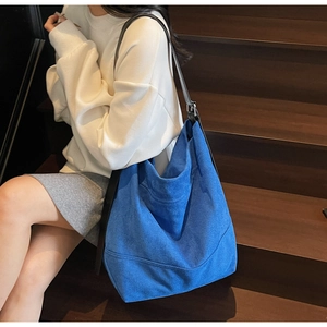 Detail of blue matte suede tote bag featuring adjustable black strap and silver buckle