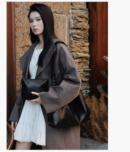 Detail of black leather tote bag with matching zipper pouch against stone building