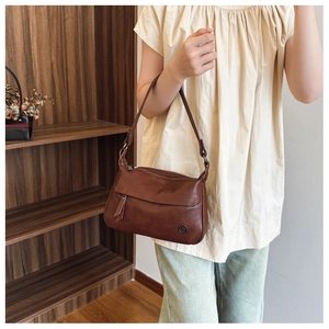 Detail of dark brown vintage shoulder bag with adjustable strap and metal logo accent