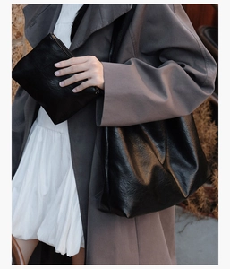 Detail of a large black faux leather tote bag and matching pouch with matte finish texture