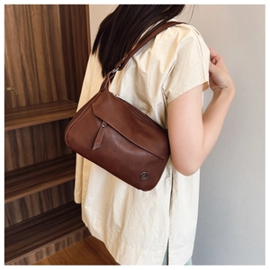 Detailed view of brown vintage square bag with metal logo and shoulder strap on model