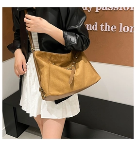 Retro mustard faux suede bucket bag with brown leather strap worn by a model