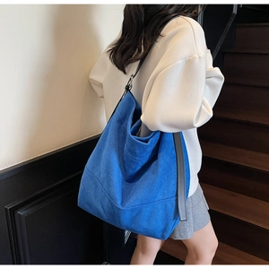 Detail of blue suede large capacity hobo bag with black leather strap on a model