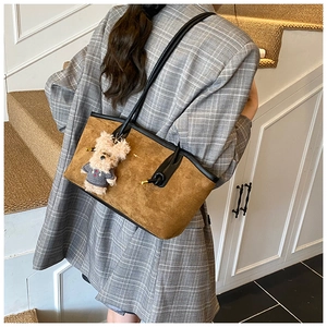 Brown suede tote bag with teddy bear pendant worn by model in grey plaid blazer