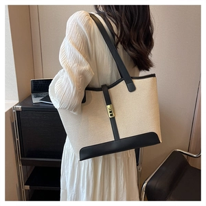 Canvas tote bag with black leather trim and gold buckle shown on a female model