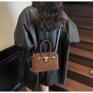 Détail de sac à main en daim marron avec doubles poignées et boucle en métal doré
