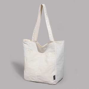 Gros plan sur un sac cabas blanc en nylon texturé avec poche avant et étiquette