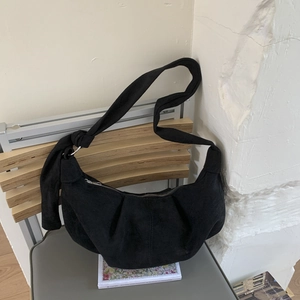 Close-up of matte suede dumpling bag featuring pleated bottom and decorative knot detail