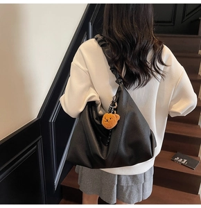 Détail du grand sac hobo noir avec pendentif ours et large bandoulière à plis souples