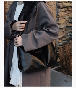Detail of black leather tote bag with subtle texture and wide strap for daily commute