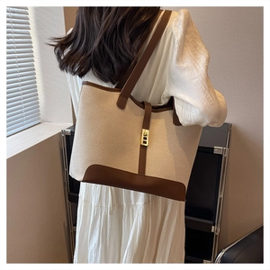 Model wearing a large canvas tote bag with brown leather trim in elegant natural light