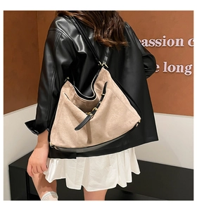 Detail of large beige suede and black leather patchwork tote bag worn over the shoulder