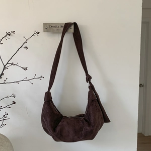 Close-up of vintage dark brown suede croissant bag with knotted strap and zipper detail