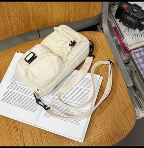 Detail view of cream crossbody bag with wrinkled fabric texture and drawstring pockets