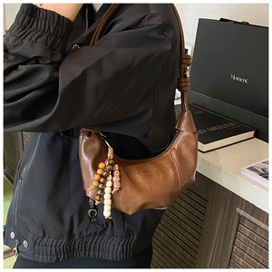 Detail of vintage brown crescent bag with knotted strap and retro beaded pendant