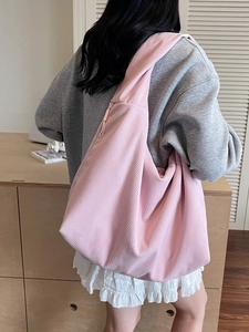 Grand sac hobo rose en velours côtelé porté par un mannequin dans un intérieur cosy