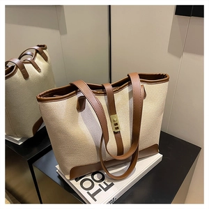 Close-up of the large canvas tote bag showing beige fabric and brown leather textures