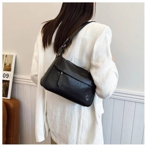 Side view of black lychee grain faux leather shoulder bag worn with white blazer
