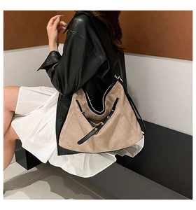Detail of minimalist khaki suede hobo bag with black leather trim and gold rings