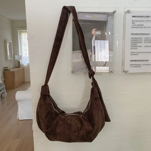 Close-up of dark brown crescent bag showing textured suede leather and knotted strap detail