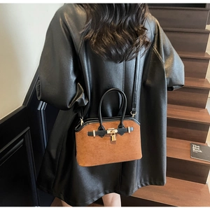 Détail du sac en daim marron avec fermoir doré et finitions en cuir noir élégantes