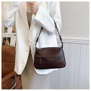 Detail of vintage brown leather square bag with metal logo and shoulder strap