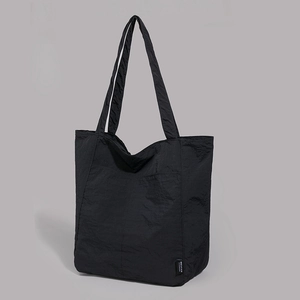 Détail d'un grand sac cabas en nylon noir avec une texture minimaliste et des bandoulières