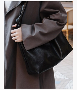 Detail of black leather tote bag with unique knotted strap and soft wrinkled texture