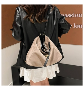 Detail of beige suede hobo bag with adjustable black leather strap and gold buckle