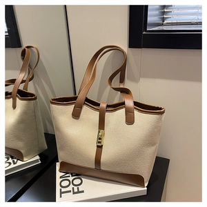 Detail of canvas tote with leather trim, metal twist-lock, and mirrored reflection view