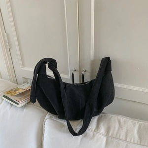 Detail shot of a black suede hobo bag featuring a distinctive wide knotted shoulder strap