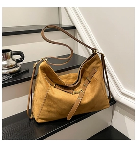 Detail of brown suede tote bag featuring adjustable strap and vintage gold buckle hardware