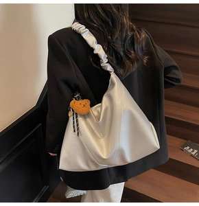 Détail du sac hobo argenté métallisé avec bandoulière froncée et breloque ours