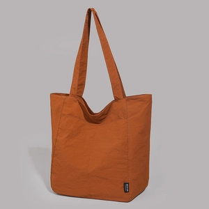 Détail du cabas en nylon caramel avec coutures latérales et étiquette logo de la marque