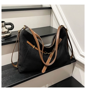 Detail view of black faux suede tote bag featuring adjustable brown leather straps with metal eyelets