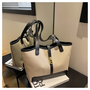 Detail of canvas tote bag featuring iconic gold metal buckle and black leather trim