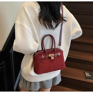 Détail du sac coquillage bordeaux avec boucle dorée et bandoulière porté par un mannequin